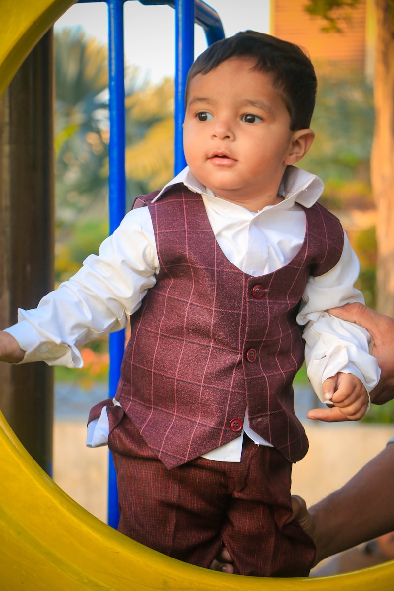 a young boy in a vest and tie standing in a playground